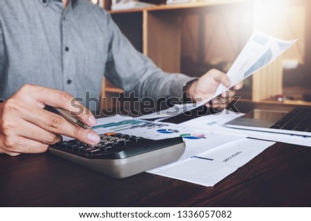 Business research loan application data concept, Asian businessmans using calculator and laptop computer  Calculate interest on loans on wooden desk in office.