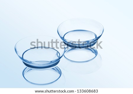 Two contact lenses with reflections on a blue background. Focus on long-distance lens. Royalty-Free Stock Photo #133608683
