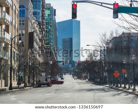 Atlanta, USA, Cityscape shot of empty road with red light, dried out trees on the side, buildings, Ferris wheel and tall building with blue tint glass
