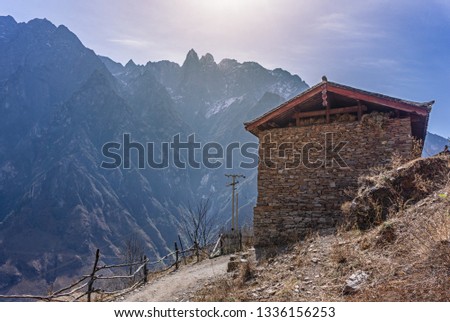 The local house built with stone arrangement with hiking trail path of Tiger Leaping Gorge and Jade Dragon snow mountainin background, Lijiang, Yunnan, China