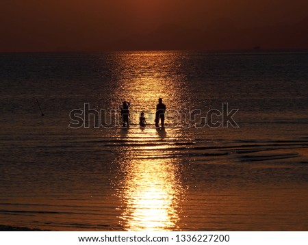 Silhouette family standing in the sea and red  sky at NATHON BEACH in sunset SAMUI ISLAND THAILAND