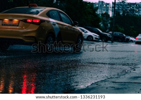 Motion car in rain with selective focus, color toned. Night road blurred, in the dark while heavy raining. Back light of car on raining road, light reflected on road. View from the level of asphalt