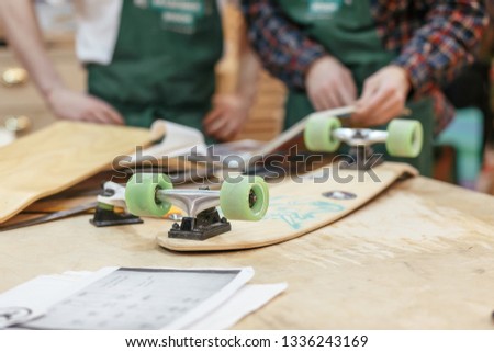 Two unknown male carpenters make a skateboard on an exclusive order. Concept hobby for youth and handmade