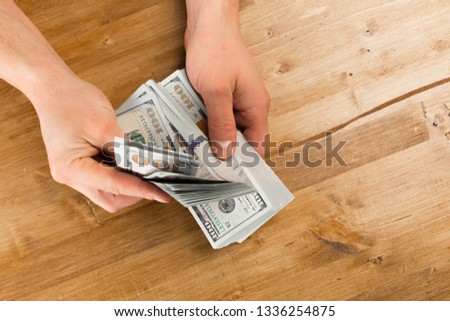 Man count the new us dollars on wooden table 