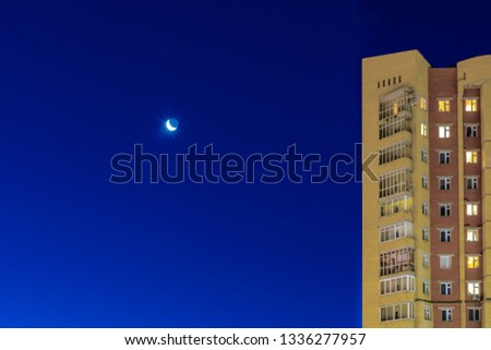 The month is shining, the month is shining and the stars are against a blue bright sky, against the background of a residential building. Template for design.