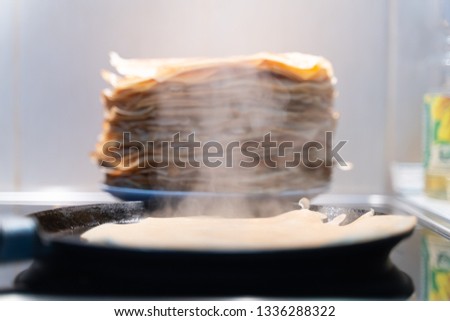 stack of ready fried pancakes as background . pancakes are fried on a black frying pan.