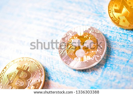 Close up photo of golden Ripple XRP, BItcoin and Monero XRM coin. Blue wood background.