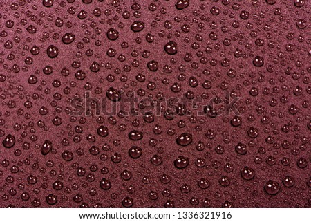 Close up of water drops on red tone background. Abstract red wet texture with bubbles on plastic PVC surface or grunge. Realistic pure water droplets condensed. Detail of canvas leather texture