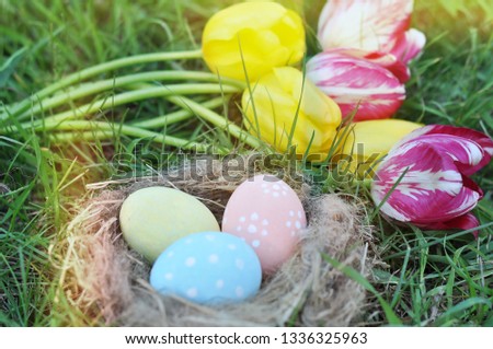 painted Easter eggs in a nest on green grass and a bouquet of tulips, an Easter card, a festive concept