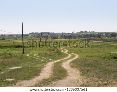 Dirt road in a field on a sunny day. Endless horizon panorama. Stock background, photo