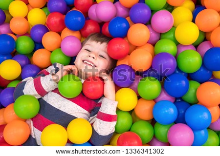 Little boy playing in dry pool with plastic balls in the nursery. Close-up leisure activities indoors. Positive emotions background. School holidays. Copy space Royalty-Free Stock Photo #1336341302