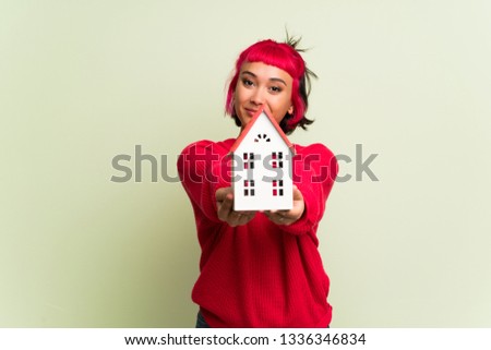 Young woman with red sweater holding a little house