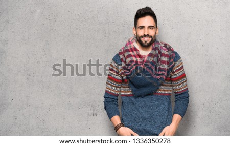 Hippie man posing and laughing looking to the front over textured wall