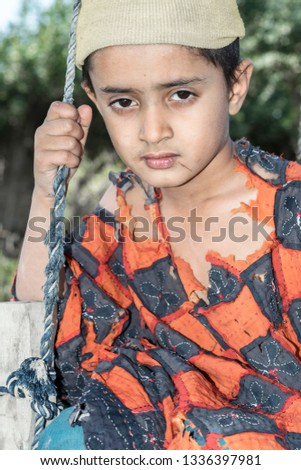 an isolated tribal boy is wearing torn wild clothes with sad expression 