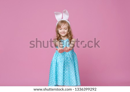 Cute little blonde girl in the shape of an Easter Bunny and a blue dress with a pea pattern. Concept of the celebration, advertising and fashion. happy Easter. Selective focus.