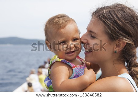 Happy mother holding girl and looking at her at summer vacation