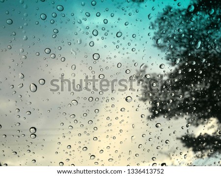 Car windshield view, raindrop on the windshield, dark storm sky is backdrop, colorful bokeh.