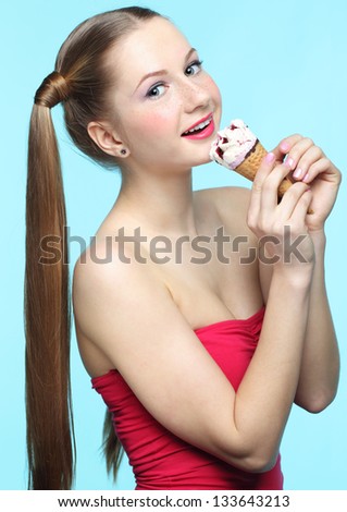 Beautiful playful young freckled girl with  ice cream on blue background