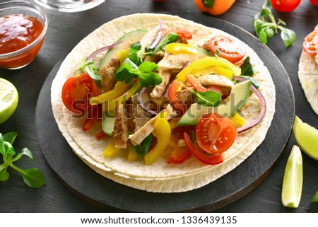 Close up of healthy tacos with grilled chicken meat and vegetables on dark stone table