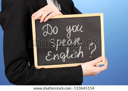 Young woman holding sign "Do you speak English?", on color background