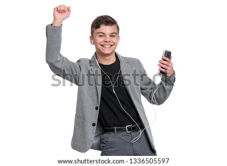 Portrait of Handsome Teen Boy with Mobile Phone and Headphones, isolated on white background. Cheerful Smiling Child dancing while listening to music. Enjoying Cute modern Teenager in suit.
