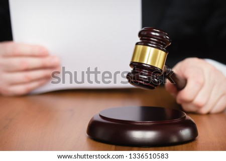 Judge's gavel in hand. Judge passes sentence. Lawyer and court. Judge hits the table with hammer. In the courtroom, the judge convicted lawyer. Royalty-Free Stock Photo #1336510583