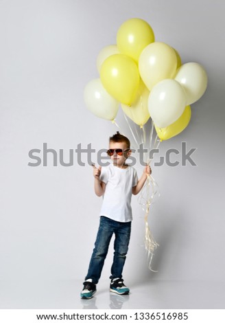 Child stylish boy holding the bunch of balloons over the white background