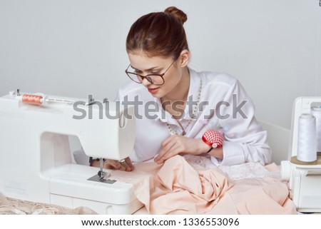    woman in glasses sews clothes on a sewing machine                            