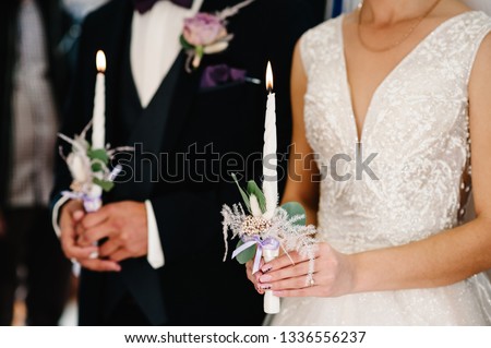 The bride, groom holds in hands wedding candle. Burn candle. Spiritual couple holding candles during wedding ceremony in christian church. close up.