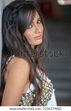 Portrait photograph of young Indian model with long black hairs wearing white ethnic dress