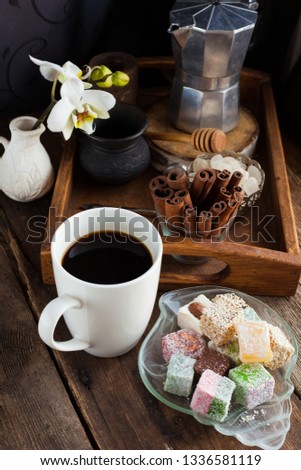 Coffee still life. White cup of coffee and oriental sweets - "Rakhat Lukum" - homemade candies on a plate.