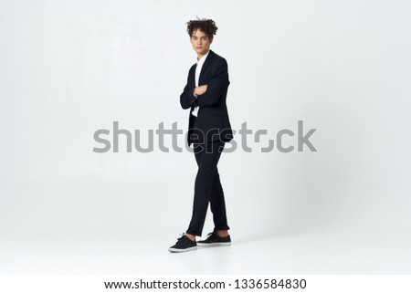 A man in a suit stands in full growth on a gray office background