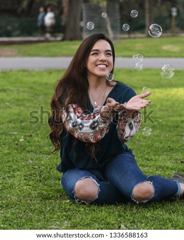 Young high school girl posing on a grassy field for graduation pictures