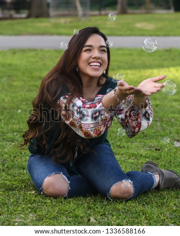Young high school girl posing on a grassy field for graduation pictures