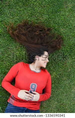 Young and beautiful high school girl posing for graduation pictures in the grass and park