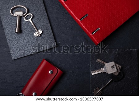 red notepad with keys on black background, top view flat lay