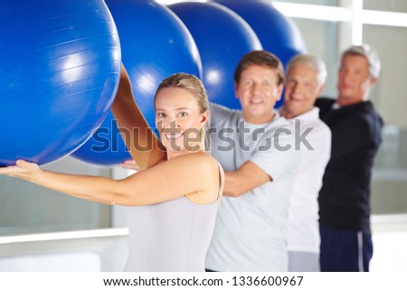 Group of seniors smiling while exercising in rehab center with gymnastics balls