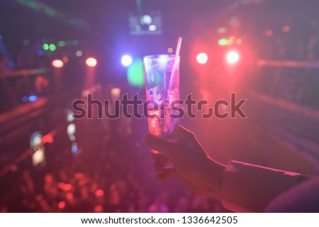 young woman holding a glass with cocktail in disco lights. Night life concept