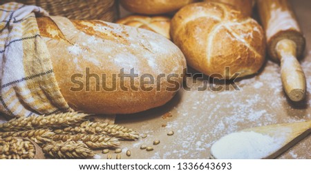 Close-up view of freshly baked bread on a rustic background with wheat and flour. Bakery and grocery concept. Photo in retro style.