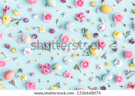 Easter eggs, colorful flowers on pastel blue background. Easter, spring concept. Flat lay, top view