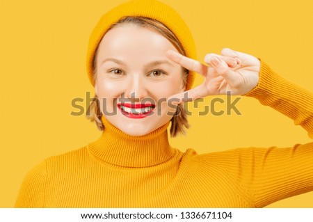 Young beautiful woman on yellow background smiling with happy face showing victory sign. 