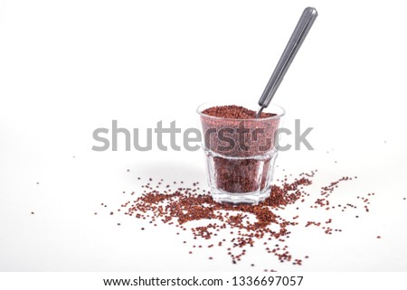 red quinoa in glass and spoon  isolated on white background