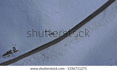 Aerial drone top view photo of snowed mountain curved - snake asphalt road crossing in beautiful winter scene
