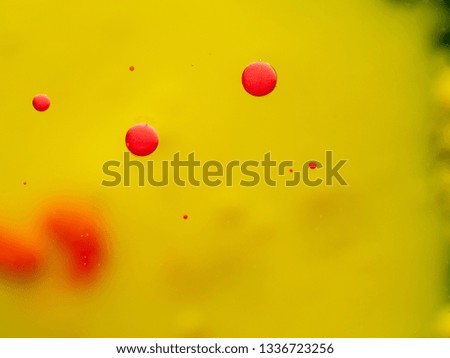 Red bubbles and spots on yellow background. Close up macro shot. Blurred background. Selective soft focus. Abstract background of paint drops and spots. Red spheres in yellow space