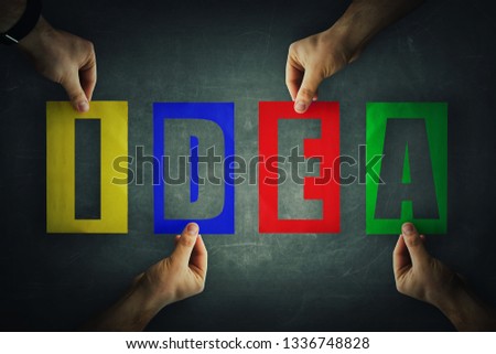 Human hands holding different colored paper with idea letters text. Symbol of working together, cooperation and collaboration. Business teamwork concept. Creative partnership metaphor.
