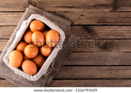 raw chicken eggs in basket on wooden background