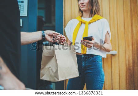 Anonimous delivery food service at home. Man courier delivered the order no name bag with food. Royalty-Free Stock Photo #1336876331