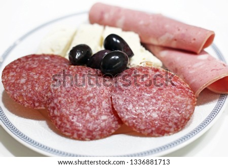 plate with cold cuts - salami and ham - olive oils and the white greek cheese called feta