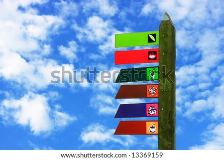 Colorful signboard with moss over cloudy blue sky.