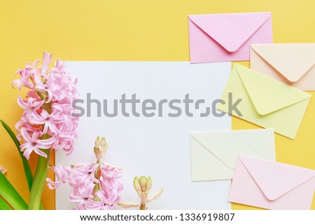 Colorful envelopes and hyacinth flowers on yellow background, copy space.